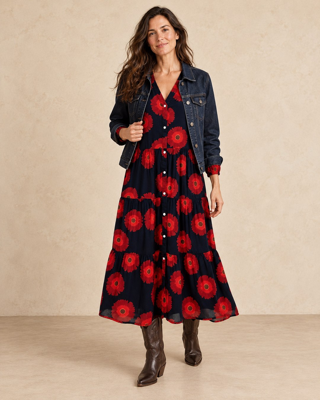 Model styling the red floral maxi dress with an open dark denim jacket and cowboy boots