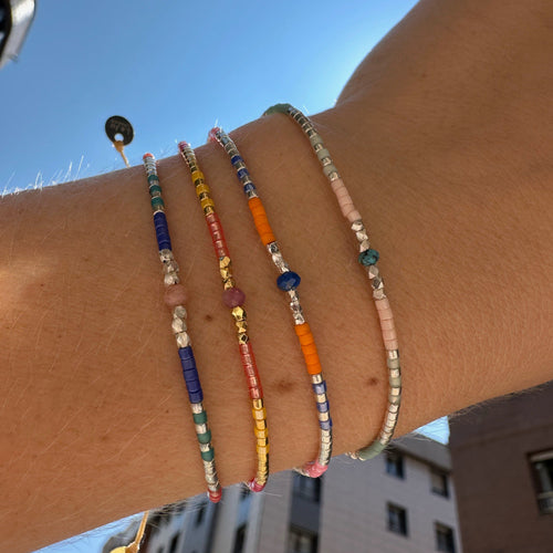   Handwoven in Colombia, this feminine bracelet features a single row of Japanese glass beads in gold and bright tones with a Lapis Lazuli stone of strenght and discipline in the centre.  Wear this stylish bracelet alone or as a part of a bracelet layering combination, with your favourite jeans & t-shirt!  Details:  - Japanese glass beads  - Silver faceted beads  -Lapis lazuli  - Width: 2mm  - Adjustable bracelet 