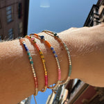   Handwoven in Colombia, this feminine bracelet features a single row of Japanese glass beads in gold and bright tones with a Peach sun-stone of strenght and discipline in the centre.  Wear this stylish bracelet alone or as a part of a bracelet layering combination, with your favourite jeans & t-shirt!  Details:  - Japanese glass beads  - Silver faceted beads  -Peach Sun stone  - Width: 2mm  - Adjustable bracelet 